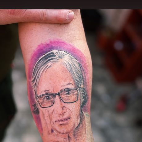 Retrato cicatrizado de una señora con lentes, tatuado en un antebrazo.