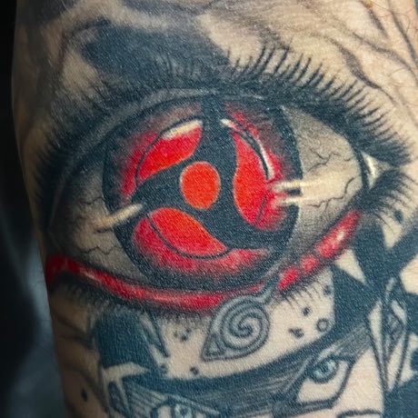 Un ojo de gran tamaño con detalles en rojo, cicatrizado en un brazo.